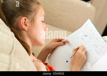 Jeune fille écrit essai / faire des devoirs / dans journal Banque D'Images