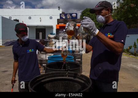 (140801) -- SANTO DOMINGO, 1 août 2014 (Xinhua) -- les employés de la Direction générale des douanes (DGA, pour son sigle en espagnol), verser de l'alcool après avoir été saisis, à Santo Domingo, la République dominicaine, le 31 juillet 2013. La DGA a détruit le jeudi 2000 cartons de whisky et de boissons alcoolisées, a saisi lorsqu'il est saisi par la contrebande sur le territoire national. Les boîtes de 2000, équivalent à 16 723,13 litres de différents types de boissons alcoolisées, avec une valeur approximative de 11 793 331,76 pesos dominicains, a informé l'ingénieur Fernando Fernandez, chef de la DGA. (Xinhua/Roberto Guzma Banque D'Images