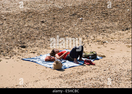 Jeune femme endormie au soleil sur la plage à Whitstable Kent England UK Banque D'Images