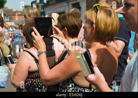 Les personnes utilisant l'ordinateur tablette numérique & smartphones que des caméras pour photographier Oyster Festival parade à Whitstable Kent England UK Banque D'Images