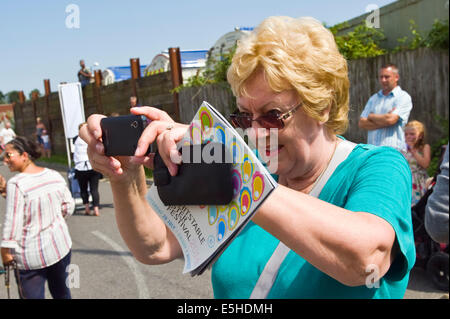 Lady en utilisant l'appareil photo Samsung smartphone comme pour photographier Oyster Festival à Whitstable Kent England UK Banque D'Images