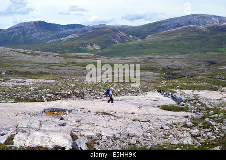 Homme seul Walker Hill en descendant la montagne écossaise avec Conival Breabag Canisp et dans l'arrière-plan. Banque D'Images