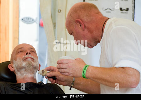 Malmesbury, UK, 26/07/2014 : Atmosphère au monde - WOMAD de la musique, des arts et de la danse. Un homme prend un rasage humide. Photo par Julie Edwards Banque D'Images