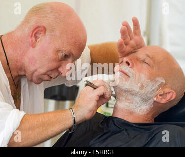 Malmesbury, UK, 26/07/2014 : Atmosphère au monde - WOMAD de la musique, des arts et de la danse. Un homme prend un rasage humide. Photo par Julie Edwards Banque D'Images