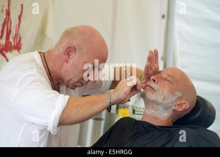 Malmesbury, UK, 26/07/2014 : Atmosphère au monde - WOMAD de la musique, des arts et de la danse. Un homme prend un rasage humide. Photo par Julie Edwards Banque D'Images