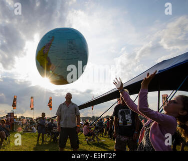 Malmesbury, UK, 25/07/2014 : Atmosphère au monde - WOMAD de la musique, des arts et de la danse. Une famille jouent avec un globe gonflable dans la lumière du soir. Photo par Julie Edwards Banque D'Images