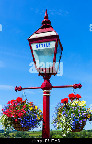 Paniers de fleurs suspendus à régler de la gare, début de la Régler Carlisle Railway, North Yorkshire, UK Banque D'Images