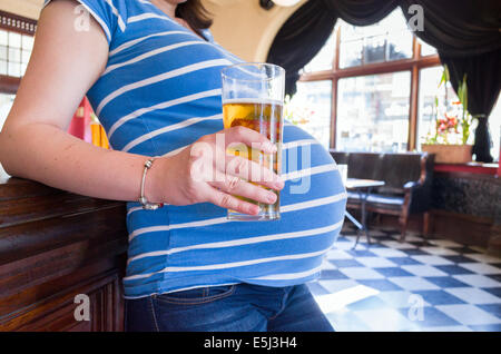 Femme enceinte de boire une pinte de bière dans un pub, London, England, UK Banque D'Images