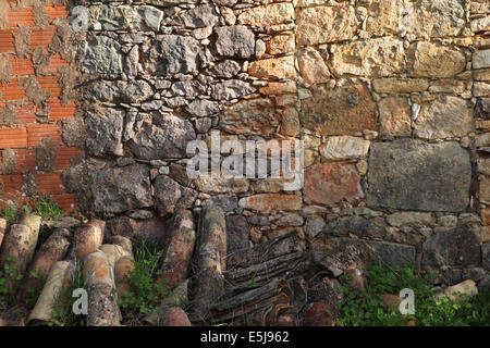 Détail d'un mur extérieur d'une ruine dans la campagne de l'Algarve montrant en pierres et débris de brique rouge. Banque D'Images