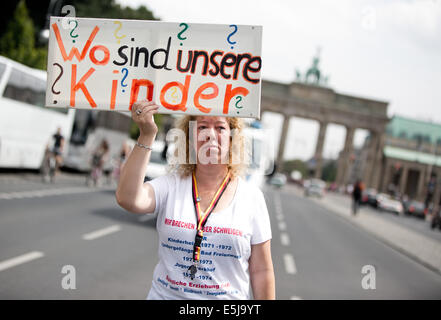 Berlin, Allemagne. 07 août, 2014. Les participants à une manifestation sur le thème "Les victimes oubliées de la réévaluation de la demande régime' protester contre la porte de Brandebourg à Berlin, Allemagne, 02 août 2014. L'organisation est l'organisation 'Hilfe für die Opfer von Zwangsadoptionen-DDR' (l'aide aux victimes de l'adoption forcée de la RDA) en coopération avec l'union des associations de victimes contre la tyrannie communiste. Photo : JOERG CARSTENSEN/dpa/Alamy Live News Banque D'Images