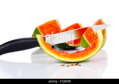 Couteau de cuisine coincé dans un morceau de melon d'isolé sur fond blanc Banque D'Images