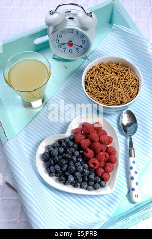 Saine alimentation élevée en fibres alimentaires avec petit déjeuner bol de céréales de son et de baies sur plaque coeur blanc sur bleu aqua bac vintage Banque D'Images