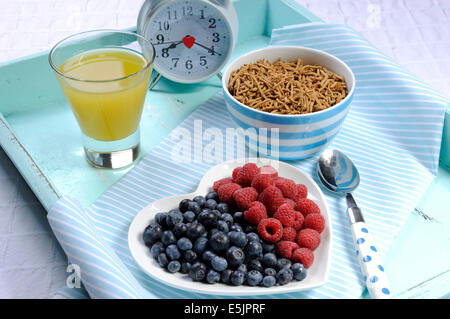 Saine alimentation élevée en fibres alimentaires avec petit déjeuner bol de céréales de son et de baies sur plaque coeur blanc sur bleu aqua bac vintage Banque D'Images