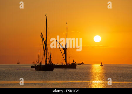 L'estuaire de Swale près de Faversham, Kent, UK 3 Août, 2014. Le soleil se lève sur les chalands à Thames historiques amarrés dans la rigole de l'estuaire. Une fois qu'une vision commune le long de la côte de la Grande-Bretagne au début de la WW1, il y a 100 ans, très peu de ces bateaux demeurent. Deux sont vus à l'ancre avec un autre à l'horizon après le week-end 42e match barge Swale. Le temps est sur le point de changer avec les prochains jours Voir la pluie pendant une bonne partie du pays. Banque D'Images