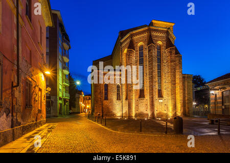 La façade illuminée de l'église catholique sur la rue pavées étroites au début de la matinée à Alba, Italie. Banque D'Images