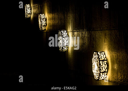 Quatre alignés des lumières décoratives de la réflexion sur un mur de pierre. Banque D'Images