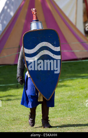 Blindage contre un volley de flèches à Beeston, Cheshire, Royaume-Uni 3rd août 2014. Réacteur armé avec bouclier, Chevalier blindé médiéval, se défendant contre les archers volant de flèches, au Tournoi tenu au Château de Beeston à Cheshire, en Angleterre. Historia Normannis un groupe de reconstitution médiévale datant de 12th ans a fourni des équipes de chevaliers hautement qualifiés, envoyées par chaîne et alimentées par l'adrénaline, pour se rencontrer de front avec l'écusson et le club. Reconstitution des entrailles d'Enrish au site du patrimoine anglais. Banque D'Images