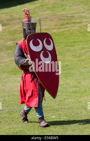 Blindage contre un volley de flèches à Beeston, Cheshire, Royaume-Uni 3rd août 2014. Réacteur armé avec bouclier, Chevalier blindé médiéval, se défendant contre les archers volant de flèches, au Tournoi tenu au Château de Beeston à Cheshire, en Angleterre. Historia Normannis un groupe de reconstitution médiévale datant de 12th ans a fourni des équipes de chevaliers hautement qualifiés, envoyées par chaîne et alimentées par l'adrénaline, pour se rencontrer de front avec l'écusson et le club. Reconstitution des entrailles d'Enrish au site du patrimoine anglais. Banque D'Images