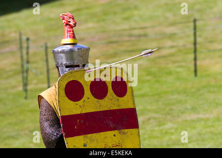 Blindage contre un volley de flèches à Beeston, Cheshire, Royaume-Uni 3rd août 2014. Réacteur armé avec bouclier, Chevalier blindé médiéval, se défendant contre les archers volant de flèches, au Tournoi tenu au Château de Beeston à Cheshire, en Angleterre. Historia Normannis un groupe de reconstitution médiévale datant de 12th ans a fourni des équipes de chevaliers hautement qualifiés, envoyées par chaîne et alimentées par l'adrénaline, pour se rencontrer de front avec l'écusson et le club. Reconstitution des entrailles d'Enrish au site du patrimoine anglais. Banque D'Images