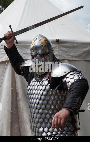 Un swordman armé dans une armure militaire complète avec un chain mail, une épée et un casque, un swordman, un combat d'épée, un guerrier, un homme, une arme, un chevalier médiéval, un chevalier traditionnel, des vêtements de protection, une martiale, un homme au château de Beeston à Cheshire, en Angleterre. Historia Normannis est un groupe de réédiction médiévale blindé datant du XIIe siècle sur le site du patrimoine anglais. Banque D'Images
