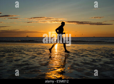Seaton Carew près de Hartlepool, Angleterre du Nord-Est, Royaume-Uni. 4e août, 2014. Météo : Jogger sur Seaton Carew beach au lever du soleil sur un glorieux lundi matin sur la côte nord-est. Credit : ALANDAWSONPHOTOGRAPHY/Alamy Live News Banque D'Images