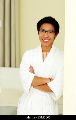 Happy asian man in bathrobe debout avec les bras croisés à la maison Banque D'Images