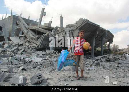 Gaza, bande de Gaza ville de Rafah. 4e août, 2014. Un garçon palestinien tient sa balle et son oiseau après qu'il les a trouvés à partir de sous les décombres de sa maison détruite, et des témoins ont déclaré que les infirmiers qui a été la cible d'une attaque aérienne israélienne, dans le sud de la bande de Gaza ville de Rafah, le 4 août 2014. Depuis le début de la guerre israélienne sur la bande de Gaza, 1 834 Palestiniens ont été tués et plus de 9 500 blessés, environ le tiers sont des civils, porte-parole du ministère de la santé Ashraf al-Qedra à Gaza a dit. Credit : Khaled Omar/Xinhua/Alamy Live News Banque D'Images