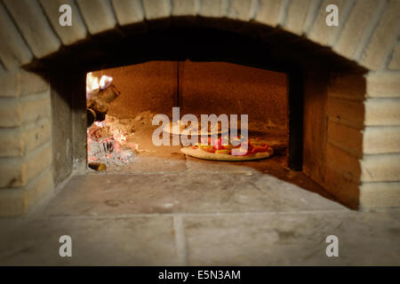 Foccacia Pizza cuisson dans un four à pizza au feu de bois brique Banque D'Images