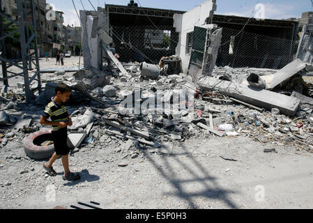 Rafah, Gaza. 4e août, 2014. Les enfants palestiniens à pied à côté de débris d'un bâtiment, qui a été touché à une frappe israélienne, à Rafah, dans le sud de la bande de Gaza. Israël a dit qu'il a unilatéralement maintenir le feu dans la plupart de la bande de Gaza le lundi afin de faciliter l'entrée de l'aide humanitaire et permettre à certains des centaines de milliers de Palestiniens déplacés par un près de quatre semaines, la guerre à la maison, à l'exception de Rafah n'est pas compris dans la trêve l'humanité. Credit : Abed Rahim Khatib/Pacific Press/Alamy Live News Banque D'Images