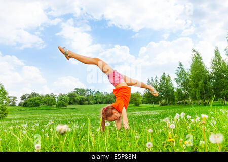 Little girl doing gymnastics on grass Banque D'Images