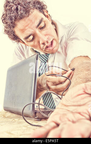 Business man in suit une dépendance à l'internet par câble USB de l'ordinateur portable dans sa veine du bras et se détend en regardant ce que Banque D'Images