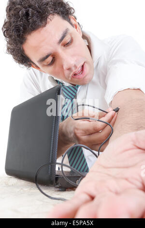 Business man in suit une dépendance à l'internet par câble USB de l'ordinateur portable dans sa veine du bras et se détend en regardant ce que Banque D'Images