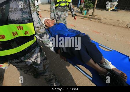 Ludian, la province chinoise du Yunnan. 5e août, 2014. Transfert des sauveteurs une personne blessée dans Longtoushan Ville de Ludian County, au sud-ouest de la province chinoise du Yunnan, le 5 août 2014. Au moins 398 personnes ont été tuées après qu'un tremblement de terre de magnitude 6,5 ébranlé la province dimanche après-midi. Credit : Xing Guangli/Xinhua/Alamy Live News Banque D'Images