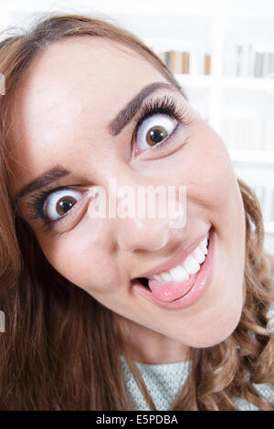 Jeune femme avec la langue qui sort et les yeux grands ouverts, crazy mad face expression, atmosphère de salon Banque D'Images