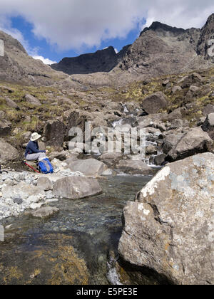 Femme assise de gros flux d'Allt Coire Lagan avec montagnes Cuillin noires au-delà,Glenbrittle, Isle of Skye, Scotland, UK Banque D'Images