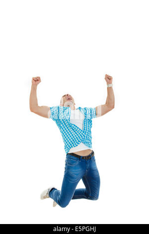 Happy handsome man in blue shirt et jeans sautant en l'air avec ses mains posées en hauteur comme un signe de succès Banque D'Images