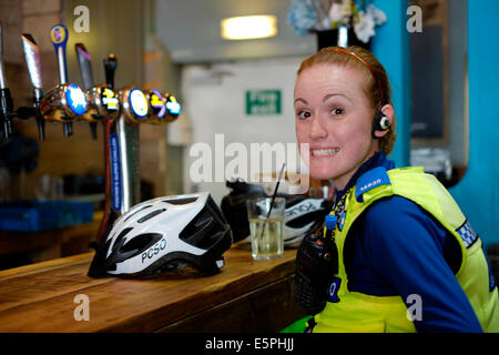 Une femme officier de police de soutien communautaire smiling dans un bar boire un jus de fruits tandis que sur les affaires de police uk Banque D'Images