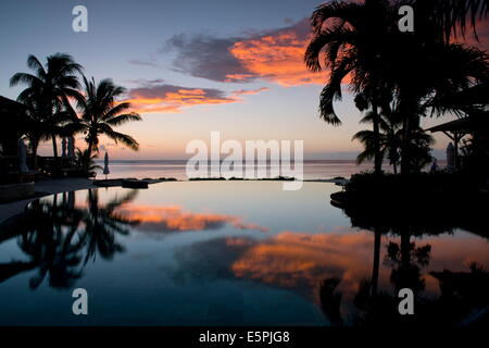 Coucher de soleil sur une piscine à débordement au Lux Le Morne Voir Le Morne Brabant, dans le sud-ouest de l'Ile Maurice, de l'Océan Indien Banque D'Images