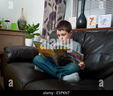 Boy reading bande dessinée sur canapé Banque D'Images