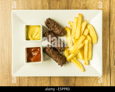 Boulettes de nourriture traditionnelle roumaine Mici et de frites avec du ketchup et de la moutarde Banque D'Images