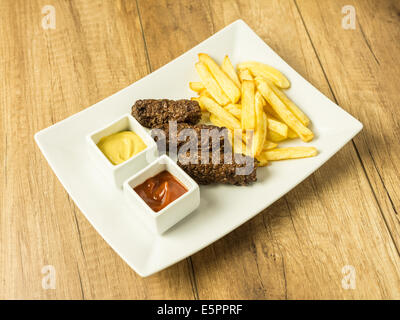 Boulettes de nourriture traditionnelle roumaine Mici et de frites avec du ketchup et de la moutarde Banque D'Images