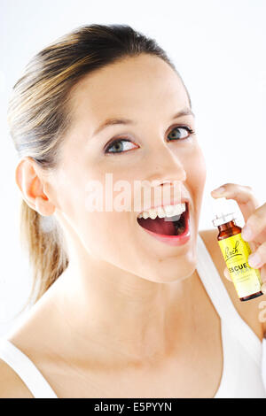 Femme à l'aide d'un Bach rescue remedy spray (extrait de fleur de liquide) pour réduire le stress et l'angoisse. Banque D'Images