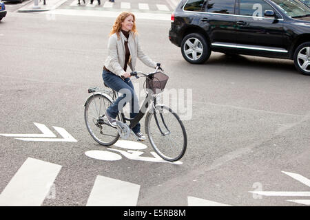 Woman riding a bicyclette dans un environnement urbain. Banque D'Images