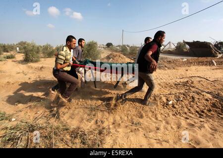 Rafah, bande de Gaza, territoire palestinien. 5e août, 2014. Les médecins portent le corps mort d'un palestinien après l'avoir sortie de sous les décombres d'une maison qui selon des témoins a été détruit pendant l'offensive israélienne, dans l'est de Rafah dans le sud de la bande de Gaza . Israël a retiré ses forces de terre en provenance de la bande de Gaza le mardi et a commencé une trêve de 72 heures avec le Hamas par l'intermédiaire de l'Égypte comme un premier pas vers des négociations sur une plus durable à la fin mois de guerre. Credit : ZUMA Press, Inc./Alamy Live News Banque D'Images