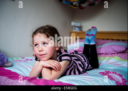 Jeune fille de 8910 en regardant par la fenêtre lying on her bed Banque D'Images