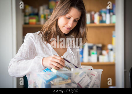 Le tri des médicaments à partir de la vieille femme son armoire à pharmacie. Banque D'Images
