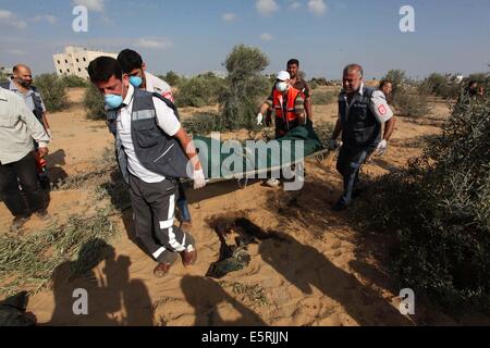 Rafah, bande de Gaza, territoire palestinien. 5e août, 2014. Les médecins portent le corps mort d'un palestinien après l'avoir sortie de sous les décombres d'une maison qui selon des témoins a été détruit pendant l'offensive israélienne, dans l'est de Rafah dans le sud de la bande de Gaza . Israël a retiré ses forces de terre en provenance de la bande de Gaza le mardi et a commencé une trêve de 72 heures avec le Hamas par l'intermédiaire de l'Égypte comme un premier pas vers des négociations sur une plus durable à la fin mois de guerre. Credit : ZUMA Press, Inc./Alamy Live News Banque D'Images