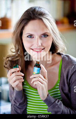 Woman smelling une bouteille d'huile essentielle. Banque D'Images
