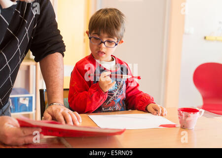 7 ans avec le syndrome de dow éduqués dans un IME, ici l'intervention éducative avec un moniteur éducateur. Banque D'Images