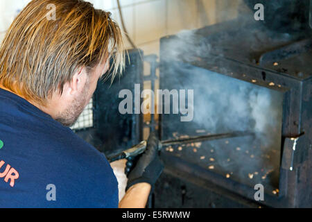 Man smoking crevettes dans un four à fumer ou Åstols Rökeri smokehouse sur l'île d'Åstol, Bohuslän, Västra Götaland, en Suède. Banque D'Images